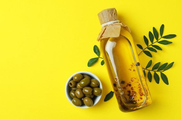 Fles olie, olijven en takjes op geel