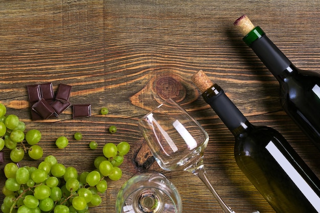 Flessen en glazen wijnchocolade en rijpe druiven op houten achtergrond