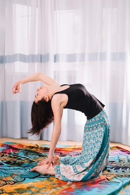 Flexibele jonge vrouw die yoga doet bij gymnastiek