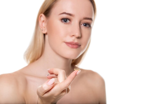 Focus op contactlens op vinger van jonge vrouw. Jonge vrouw met contactlens op vinger voor haar gezicht. Vrouw met contactlens op witte achtergrond. Gezichtsvermogen en oogzorg concept.