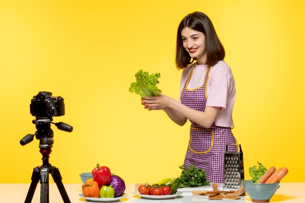 Food blogger schattige mooie chef-kok in roze schort die video opneemt voor sociale media met een sla