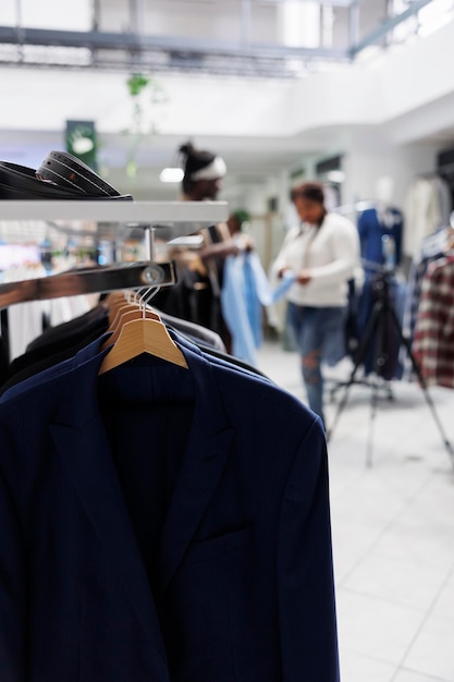 Gratis foto formele mannelijke blazers hangen aan een rek in een modeboetiek met onscherpe achtergrond. mannelijke jassen laatste aankomst op hangers en accessoires op de plank in het warenhuis close-up selectieve focus