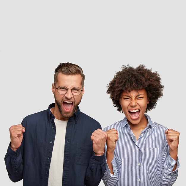 Foto van boze gemengde race jonge studenten balken vuisten van ergernis, schreeuwen wanhopig