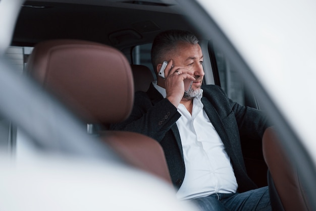 Foto van buiten het voertuig. zakelijk gesprek hebben terwijl u aan de achterkant van de moderne luxeauto zit