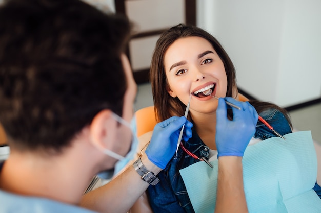 Foto van de rug, professionele tandartsmens die met patiënt in moderne kliniek werkt.