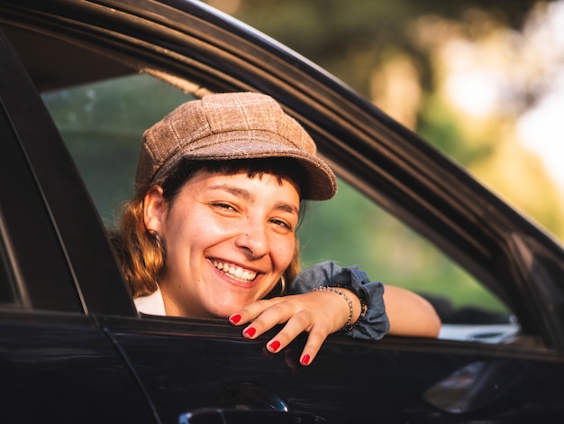 Foto van een brunette vrouw in een zwarte auto met een geweldige glimlach