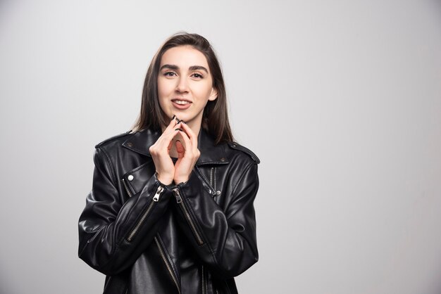 Foto van een glimlachende vrouw poseren in zwart lederen jas