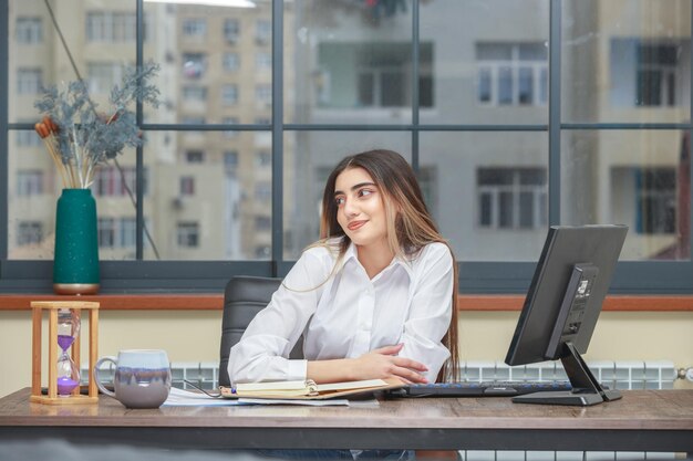 Foto van een jong meisje dat aan het bureau zit en naar de zijkant glimlacht