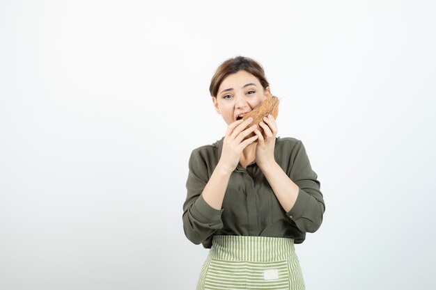 Foto van een jong meisje dat harige kokosnoot over wit probeert te eten. Hoge kwaliteit foto