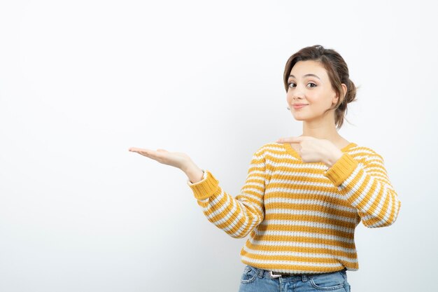 Foto van een jonge mooie vrouw model wijzend op geopende palm.