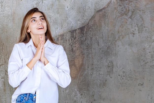 Foto van een jonge vrouw in witte blouse die tot God bidt. Hoge kwaliteit foto