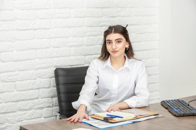 Foto van een jonge zakenvrouw die aan het bureau zit en naar de camera kijkt Foto van hoge kwaliteit