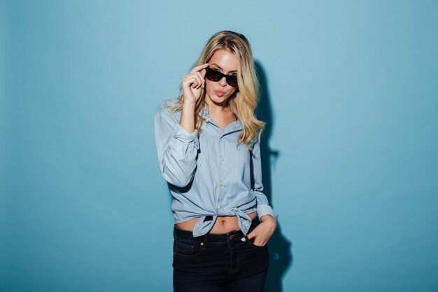 Foto van een koele blonde vrouw in shirt en zonnebril