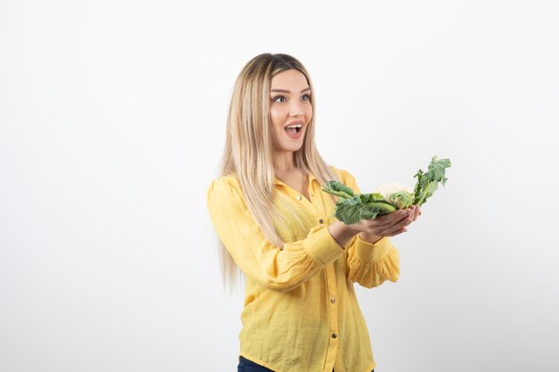 Foto van een mooi vrouwenmodel dat en bloemkool in de hand houdt.