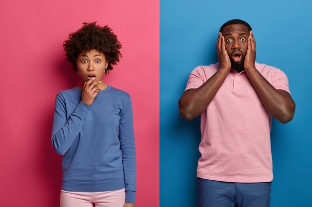 Foto van emotionele zwarte vrouw en man snakken naar adem van verwondering en schok, horen angstaanjagend nieuws, beseffen dat er een vreselijk ongeluk is gebeurd met een vriend