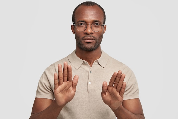 Foto van ernstige kalme Afro-Amerikaanse man toont stop gebaar