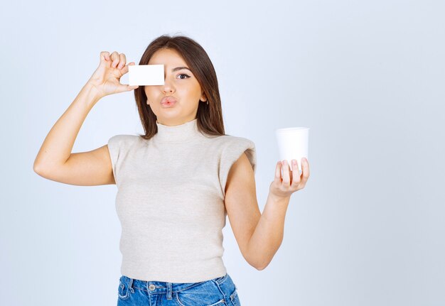 Foto van jonge dame met een plastic beker en een kaart in handen.