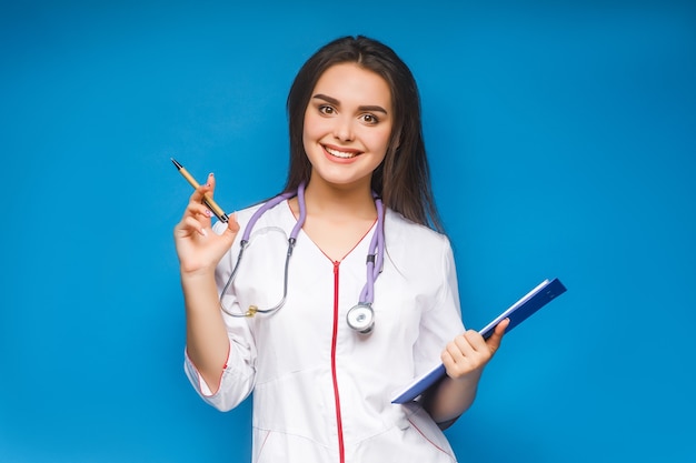 Foto van jonge dokter met stethoscoop en map op blauwe poseren.