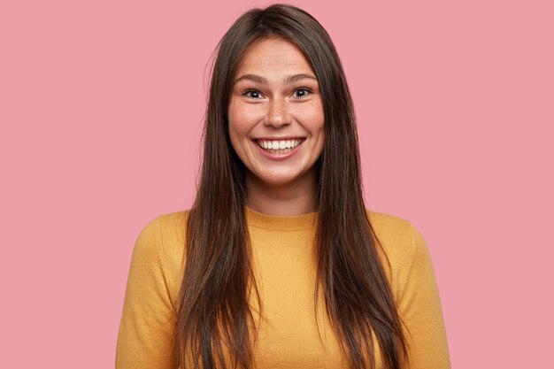 Foto van lachende vrouw met donker haar, in goed humeur, verheugt zich over promotie op het werk