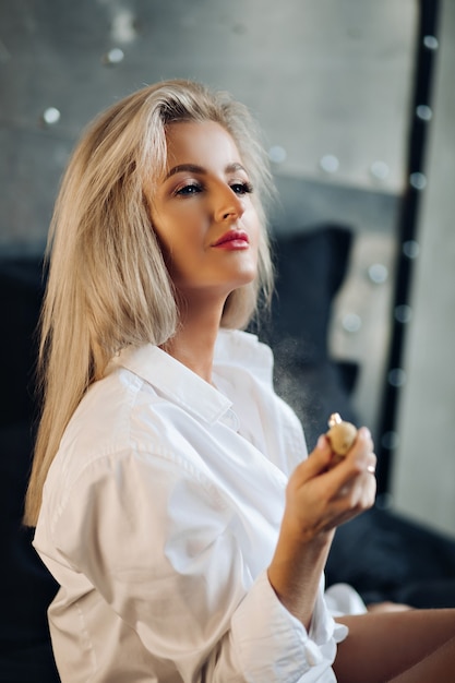 Foto van mooie jonge blanke vrouw met lang blond haar in mannenshirt poseert voor de camera in de keuken