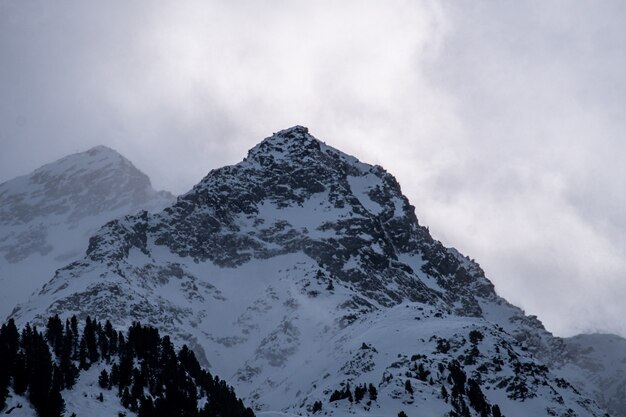 Foto van rotsachtige bergen bedekt met de sneeuw onder een bewolkte hemel en zonlicht