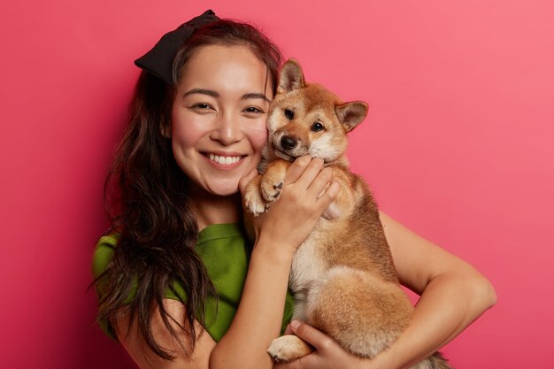 Foto van schattig jong meisje met brede glimlach, omhelst en maakt foto met mooie gehoorzame shiba inu hond, speelt graag met viervoeter.