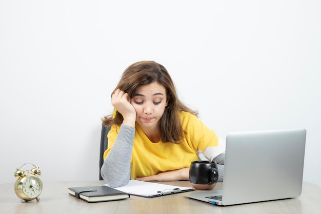 Foto van vrouwelijke kantoormedewerker zittend aan de balie met laptop en klembord. hoge kwaliteit foto