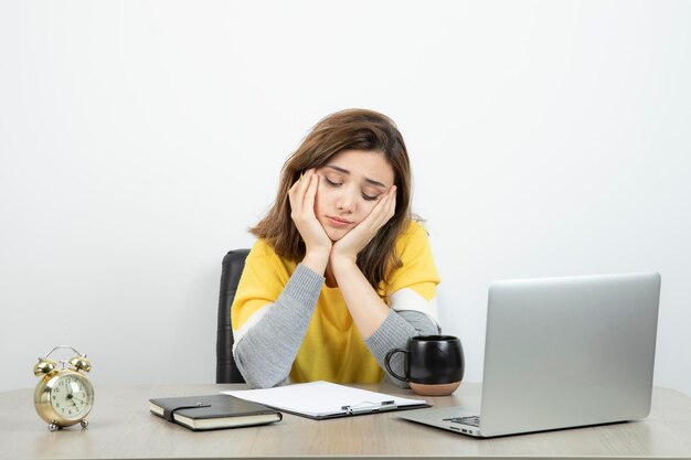 Foto van vrouwelijke kantoormedewerker zittend aan de balie met laptop en klembord. Hoge kwaliteit foto