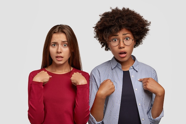 Foto van wanhopige verontwaardigde twee vrouwen wijzen naar elkaar met verontwaardigde uitdrukkingen, krijgen onverwachte taak