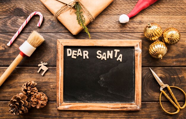Fotolijst met lieve Santa inscriptie in de buurt van huidige doos, haken en ogen en ornament ballen