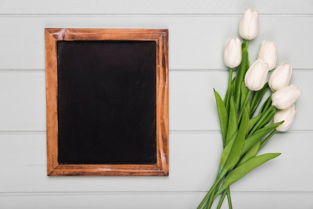 Gratis foto frame naast witte tulpen op tafel