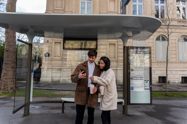 Frans stel wacht op het station om de bus te nemen en gebruikt een smartphone