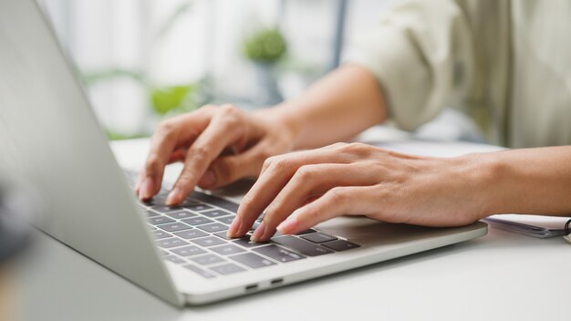 Freelance jonge zakenvrouw vrijetijdskleding met behulp van laptop die in de woonkamer thuis werkt.