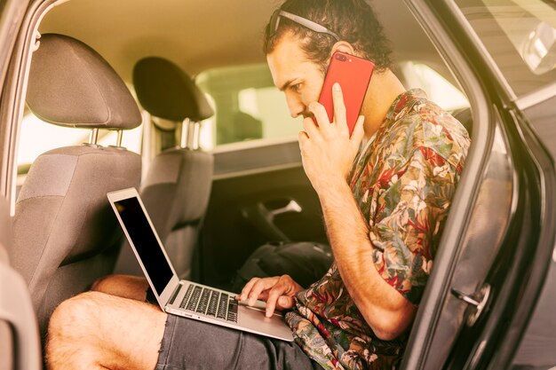 Freelancer werken met laptop en smartphone in de auto