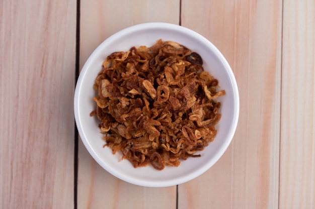 Fried onion op een witte plaat op een houten vloer.