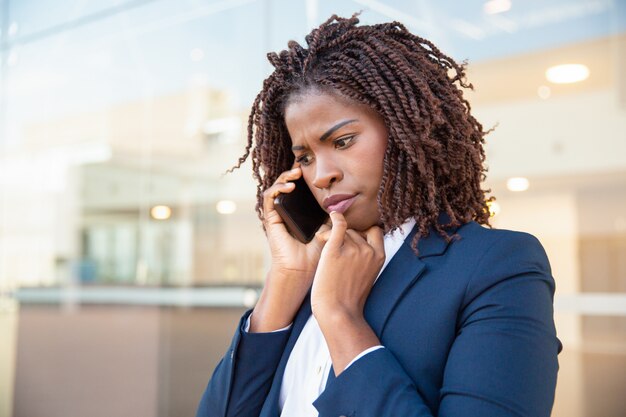 Fronsende betrokken manager die op mobiel spreekt