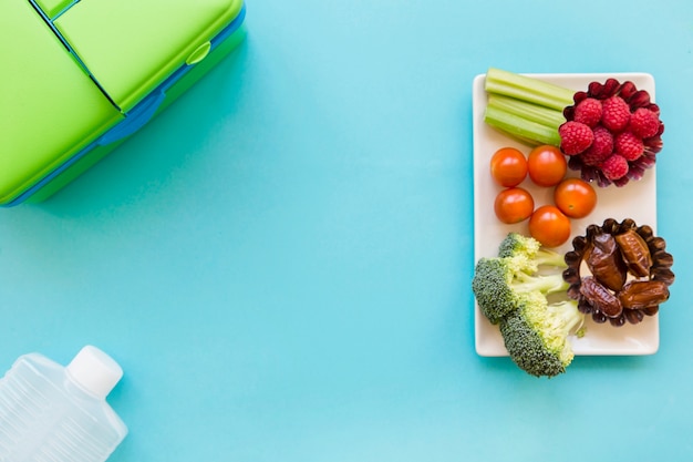 Fruit en groenten dichtbij lunchbox en fles
