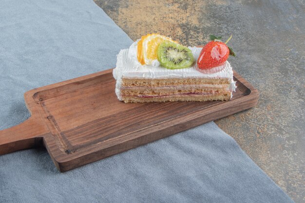 Fruit en room bedekte cakeplak op een kleine houten raad
