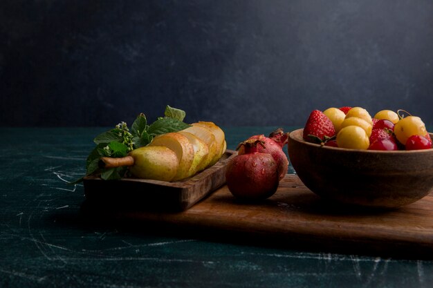 Fruitmix op een houten schotel die op blauwe ruimte wordt geïsoleerd