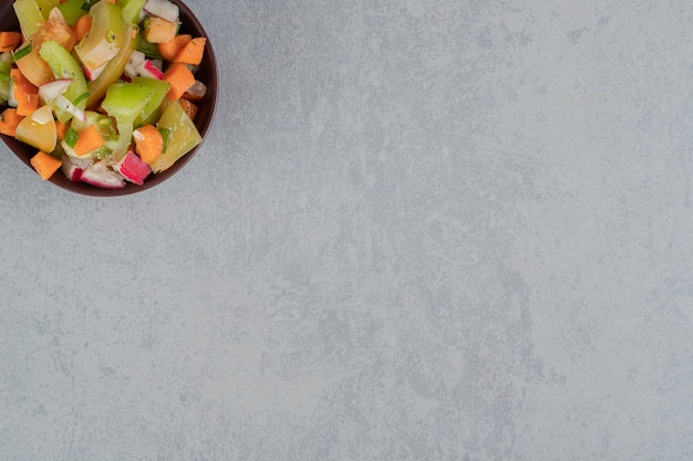 Fruitsalade in een houten kopje op een betonnen ondergrond