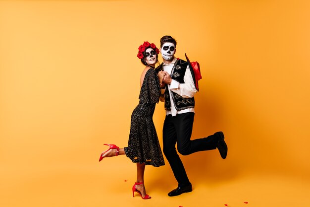 Full-length portret van grappige zombies dansen. Binnenfoto van dood paar dat Halloween samen viert.