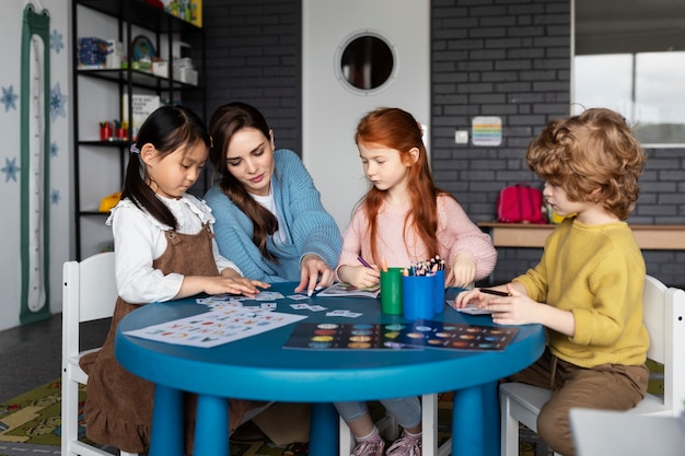 Gratis foto full shot kinderen en leraar aan tafel