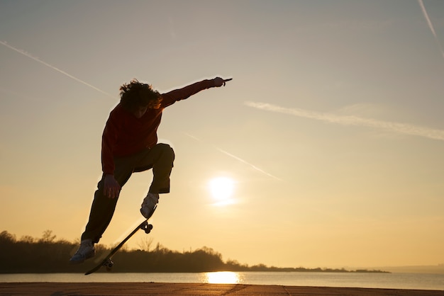 Gratis foto full shot skater poseren bij zonsondergang