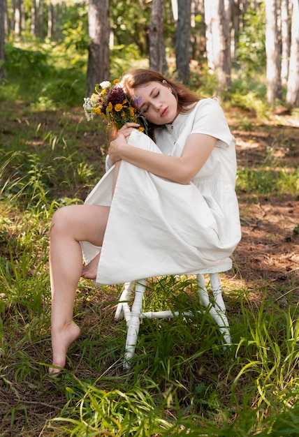 Gratis foto full shot vrouw poseren met bloemen