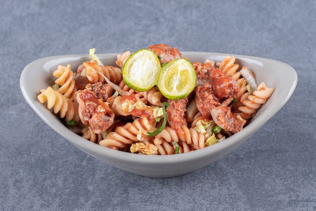 Fusilli pasta met kip in keramische kom.