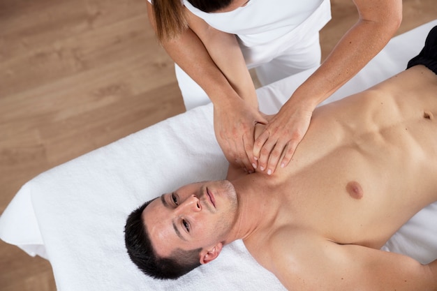 Fysiotherapeut die therapeutische massage uitvoert op mannelijke cliënt