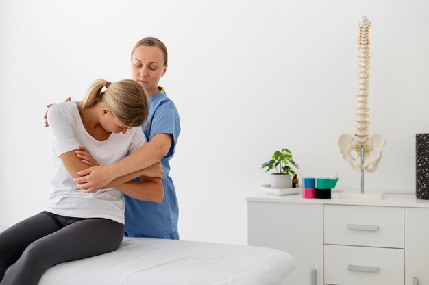 Fysiotherapeut helpt een jonge vrouwelijke patiënt in haar kliniek