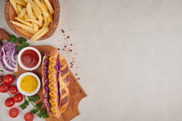 Gratis foto gastronomische gegrilde runderhotdog met kanten en frietjes. heerlijke en simpele hotdogs met mosterd, paprika, ui en nacho's. hotdogs volgeladen met diverse toppings op een sup board.