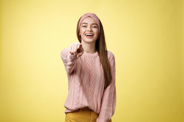 Geamuseerde charmante tedere jonge Europese vriendin die spot met plezier maken van iemand die met de vinger wijst naar...