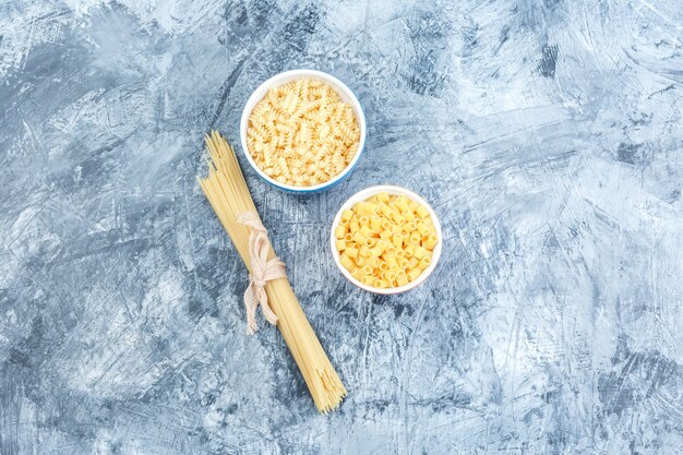 Geassorteerde pasta in witte kommen bovenaanzicht op een grijze gips achtergrond